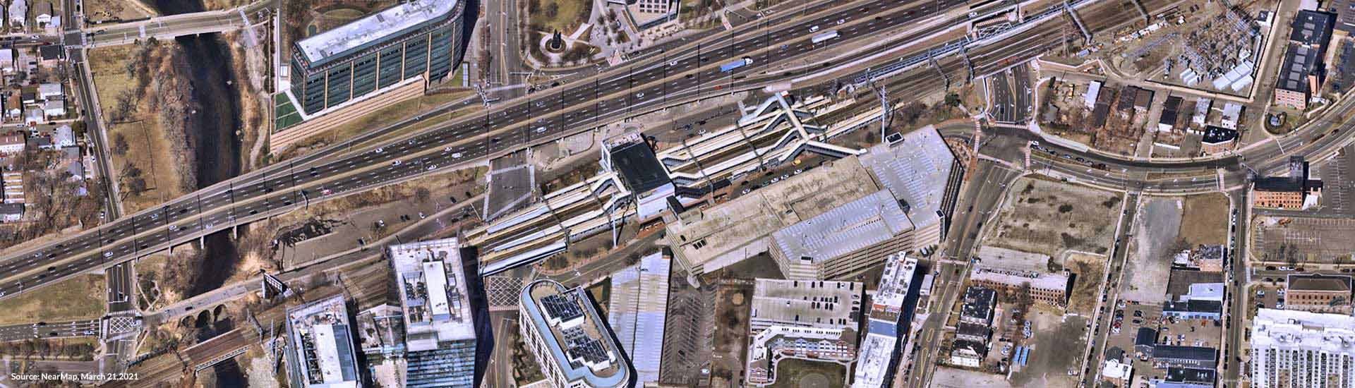 Oblique aerial view of existing STC, parking garage, adjacent buildings, and highway with traveling cars and trucks.
